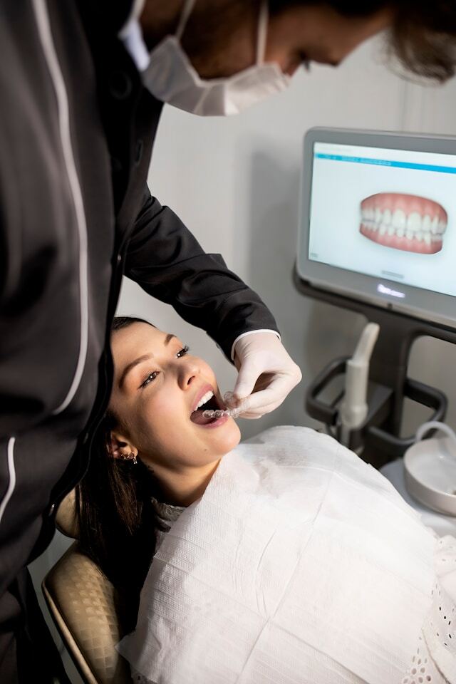 Dentist fitting retainer in patient
