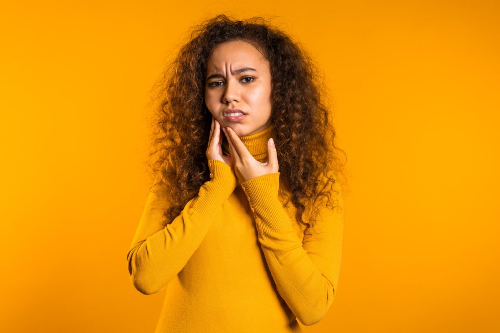 pretty woman with tooth pain on yellow studio background. Toothache, dental problems