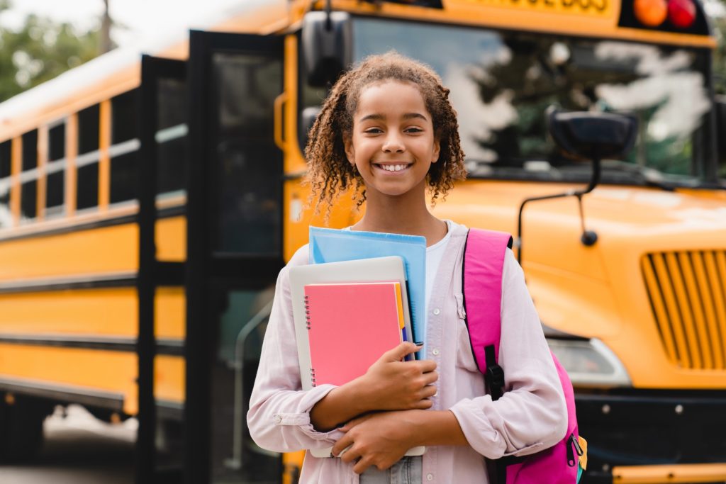 Smiling student going back to school with books and healthy teeth