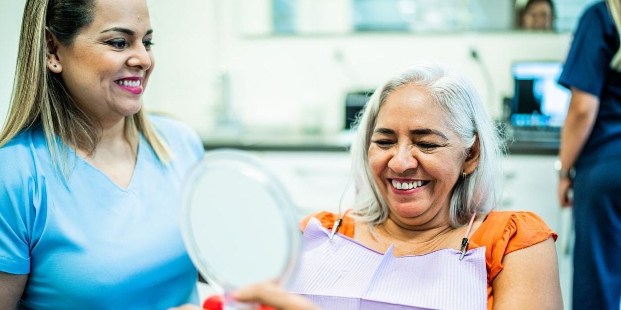Older woman smiling while sitting in dentist chair during appointment