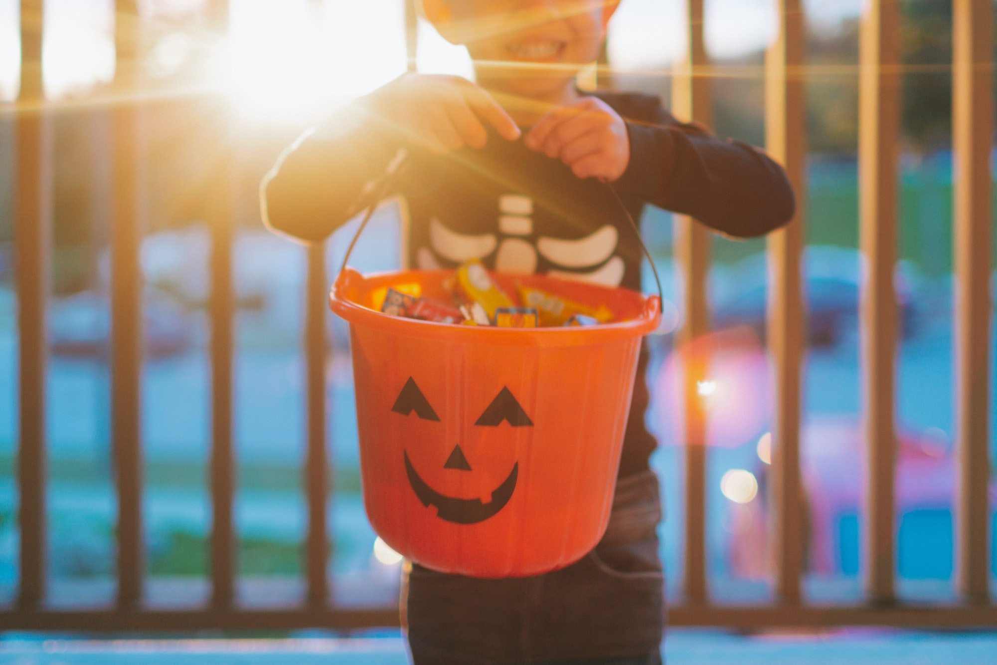 A little boy holding a bucket filled with Halloween candy.
