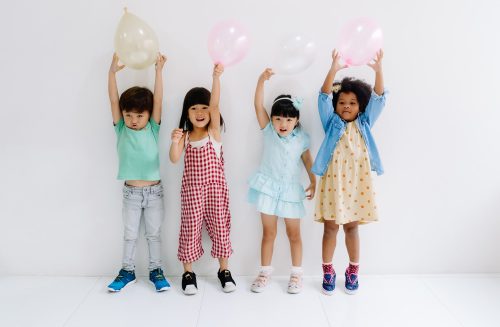 Group of adorable kids diverse cultures holding colorful balloons in party