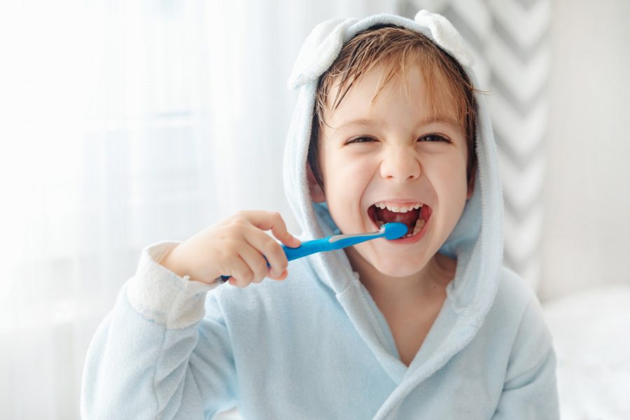 Smiling happy child brushing teeth with toothbrush. Dental hygiene of little boy, medical care.