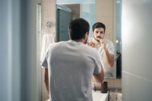 Hispanic Man Brushing Teeth In Bathroom At Morning