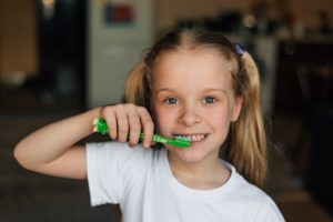 portrait child cleans forgetfulness with green toothbrush at home with smile. Hygiene and health