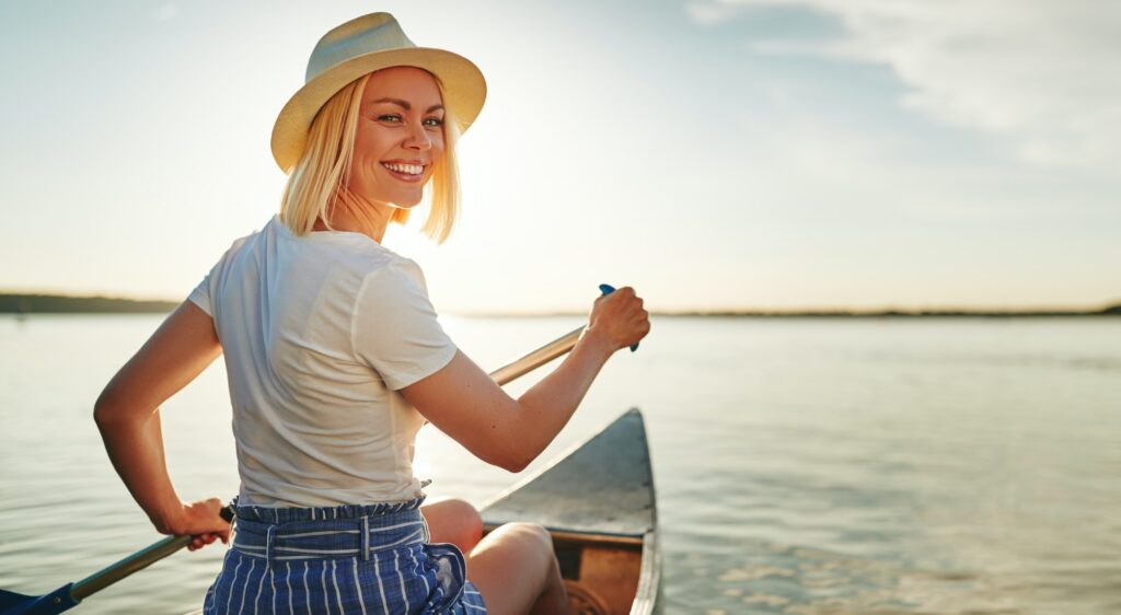 Smiling young woman canoeing on a lake in summer